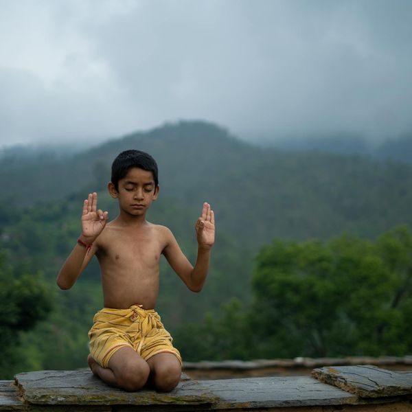 Person meditating outdoors with a serene landscape in the background.